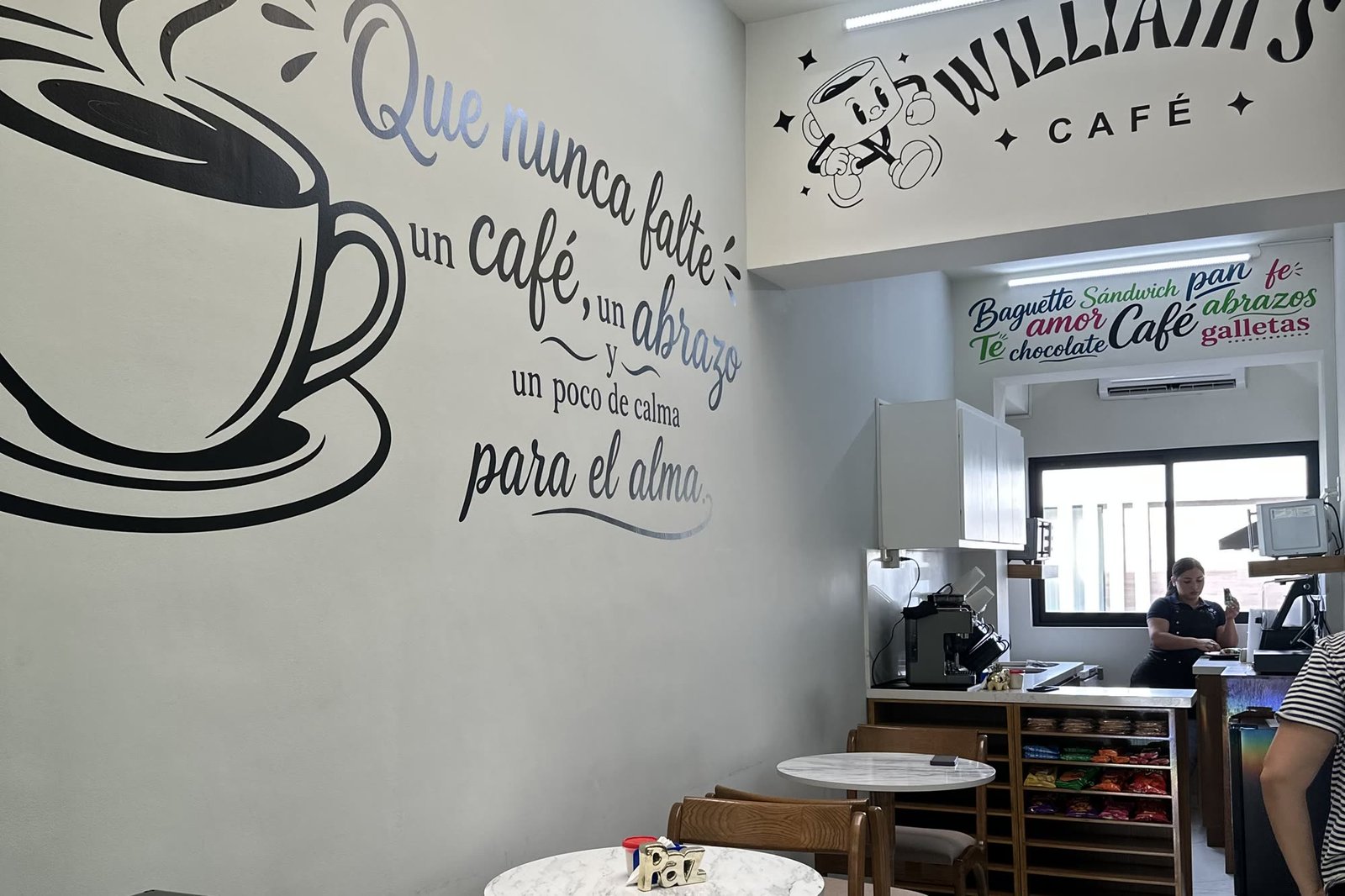 El salón del local: el mural de la taza en la pared y las mesas de mármol.